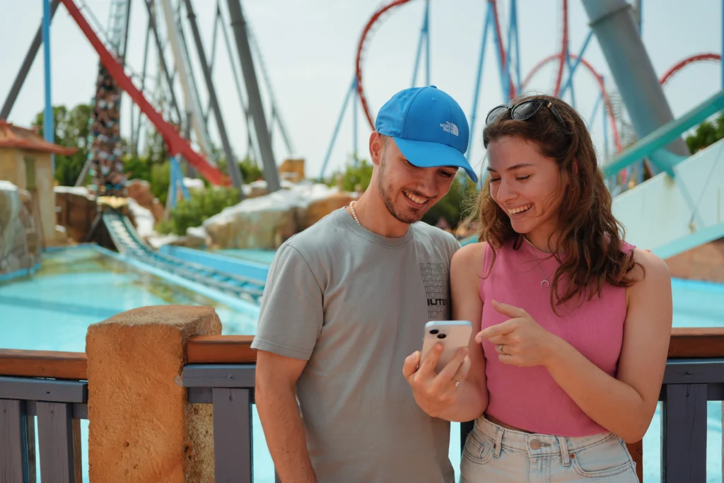 Immagine che ritrae 2 persone che sorridono guardando un telefono cellulare. Image depicting 2 people smiling while looking at a mobile phone.